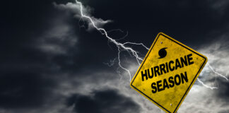 Hurricane season warning sign with lightning in stormy sky.