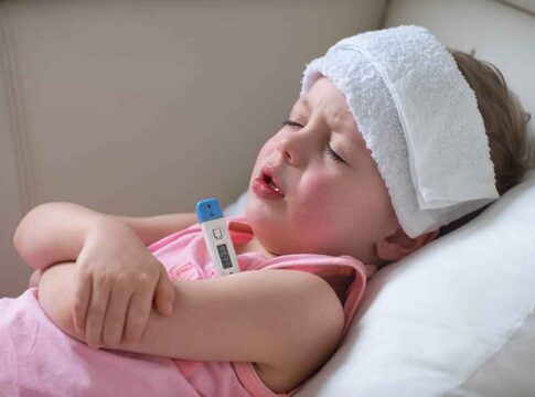 Sick child with thermometer and cold compress.
