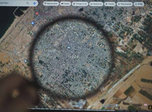 Magnifying glass over map of Gaza on a screen.
