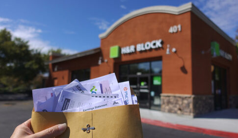 Holding tax documents outside H&R Block office.