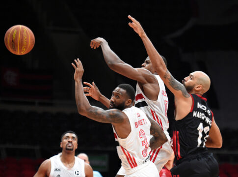 Basketball players reaching for the ball during a game.