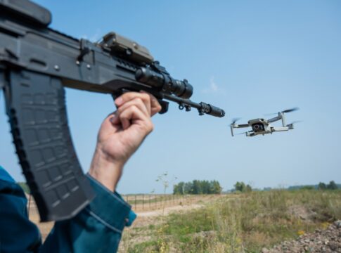 Rifle aiming at a flying drone outside on field