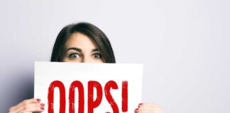 Woman holding Oops! sign with wide eyes.