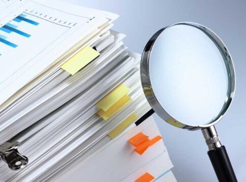 Stack of folders with a magnifying glass.