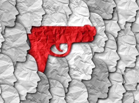 Red gun silhouette among grey paper-cut human profiles.