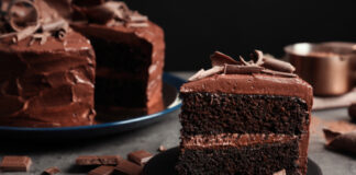 Chocolate cake slice on dark gray plate.