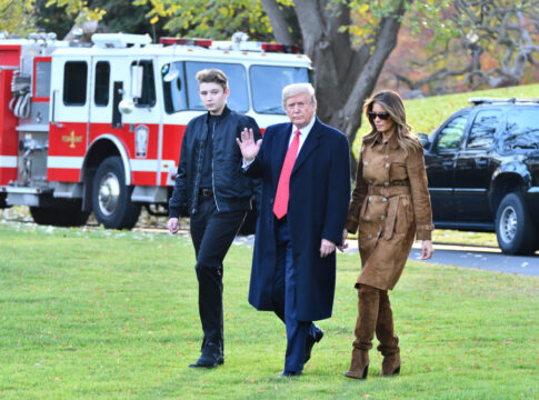 Three people walking outside near emergency vehicles