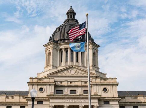 South Dakota Capitol building with American and state flags.
