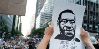 Person holding Justice for George Floyd sign at protest.