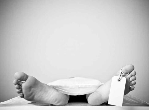 Bare feet with toe tag on body covered by sheet.