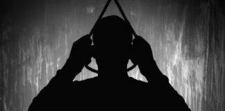 Silhouette of person holding a noose overhead.