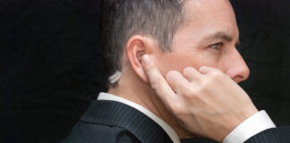 Man in suit with earpiece, looking serious.