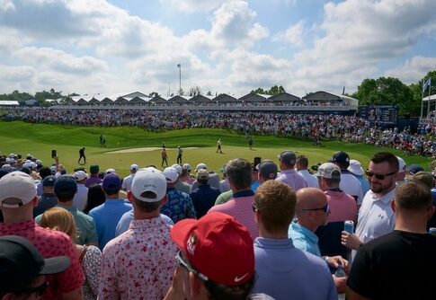 Crowd watching a golf tournament on a sunny day.