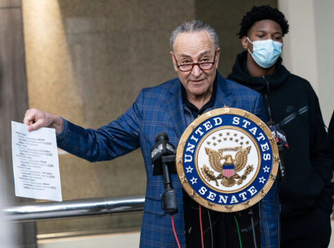 Chuck Schumer holds document at United States Senate podium.