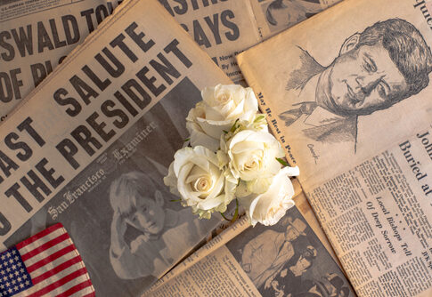 Newspapers, roses, and American flag mourning John F. Kennedy.