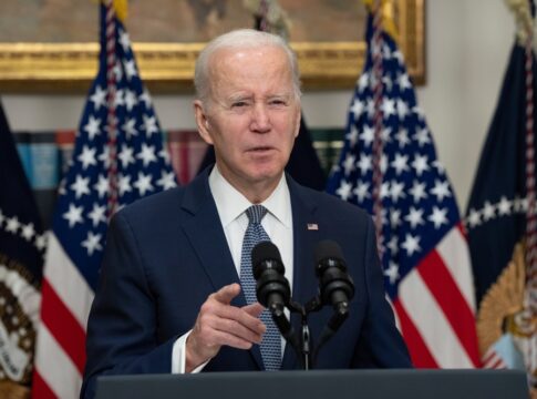 Man speaking at podium with American flags behind