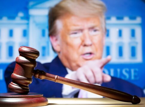 Gavel in front of a blurred person pointing