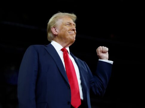 Person in suit raising fist triumphantly against dark background
