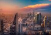 City skyline at sunset with modern skyscrapers and colorful sky.