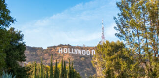 Hollywood Sign on hillside surrounded by trees, clear sky.