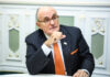 Rudy Giuliani Man in suit sitting at a table indoors