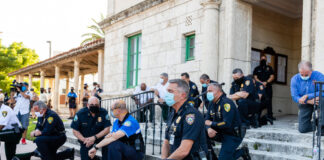 Police officers kneeling on steps, some wearing face masks.