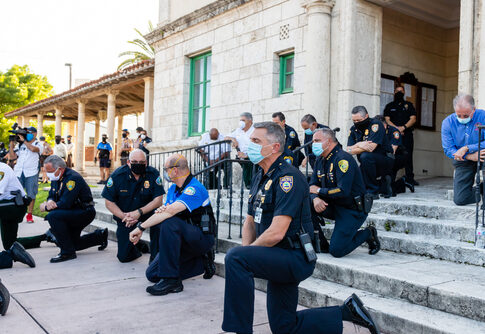 Police officers kneeling on steps, some wearing face masks.