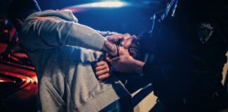 Person being handcuffed by police officer at night.