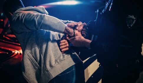 Person being handcuffed by police officer at night.