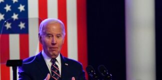 A man speaks at a podium with an American flag.