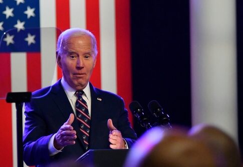 A man speaks at a podium with an American flag.