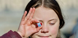 Young girl holding climate button to eye.