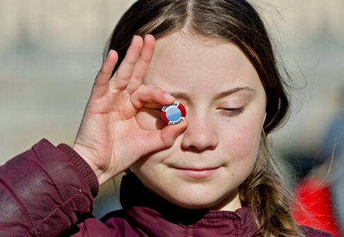 Young girl holding climate button to eye.