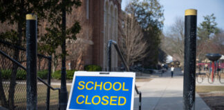 School closed sign on sidewalk near building.