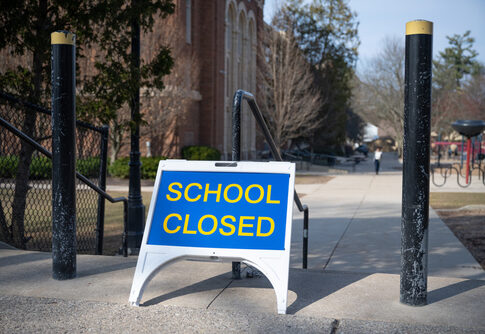 School closed sign on sidewalk near building.