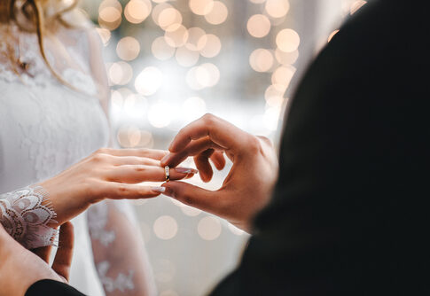 Groom placing ring on bride's finger at wedding.