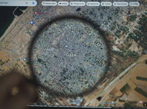 Magnifying glass over map of Gaza on a screen.