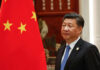 A man in a suit beside the Chinese flag.