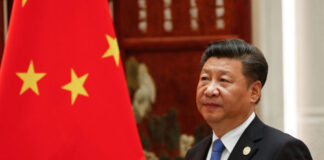 A man in a suit beside the Chinese flag.