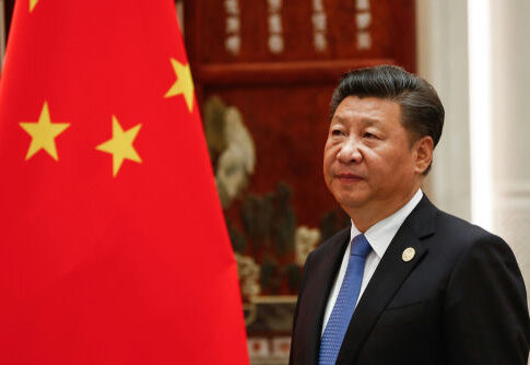 A man in a suit beside the Chinese flag.