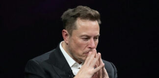 Elon Musk deep in thought, hands clasped near face.