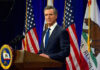 Governor Gavin Newsom speaks at podium with flags behind.