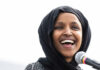 Smiling woman in hijab speaking into a microphone.