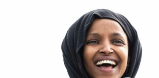 Smiling woman in hijab speaking into a microphone.
