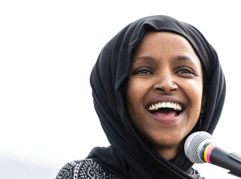 Smiling woman in hijab speaking into a microphone.