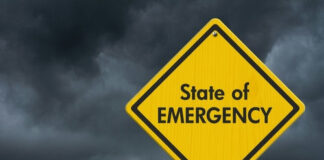 Yellow State of Emergency sign, dark stormy sky.