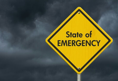 Yellow State of Emergency sign, dark stormy sky.