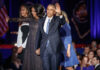 Former President Barack Obama waves while holding hands with Michelle Obama and their daughter.