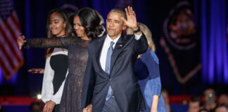 Former President Barack Obama waves while holding hands with Michelle Obama and their daughter.