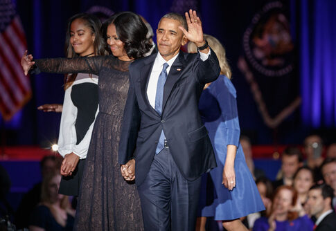 Former President Barack Obama waves while holding hands with Michelle Obama and their daughter.